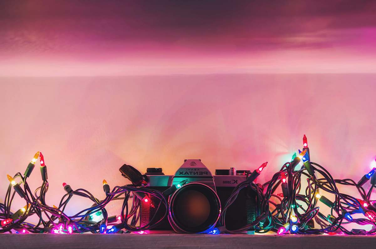 leisure activities black and silver Pentax range finder camera surrounded by string lights music